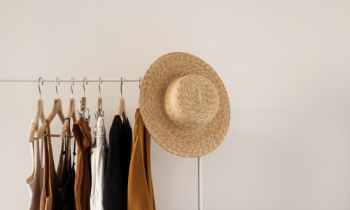 Blog Cover: Our Favorite Places to Shop Small In Indy Clothing rack with hat