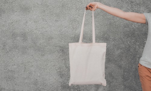 Pack an essentials bag for your Indy move Woman holding a white tote bag