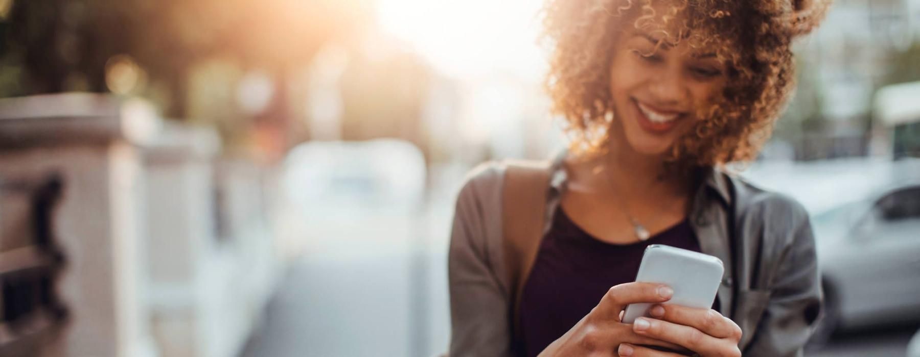 woman texts on her phone as she walks through the city